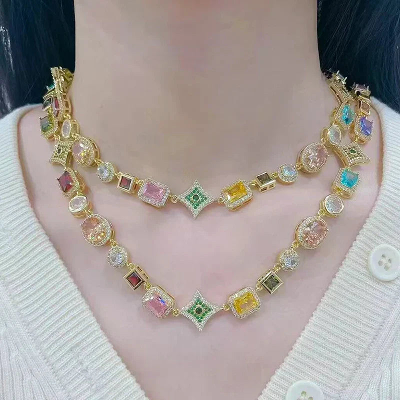 Doppelte goldfarbene Kette mit bunten Edelsteinen und funkelnden Details am Hals getragen